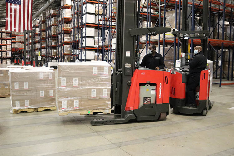 forklifts moving crates inside of a warehouse