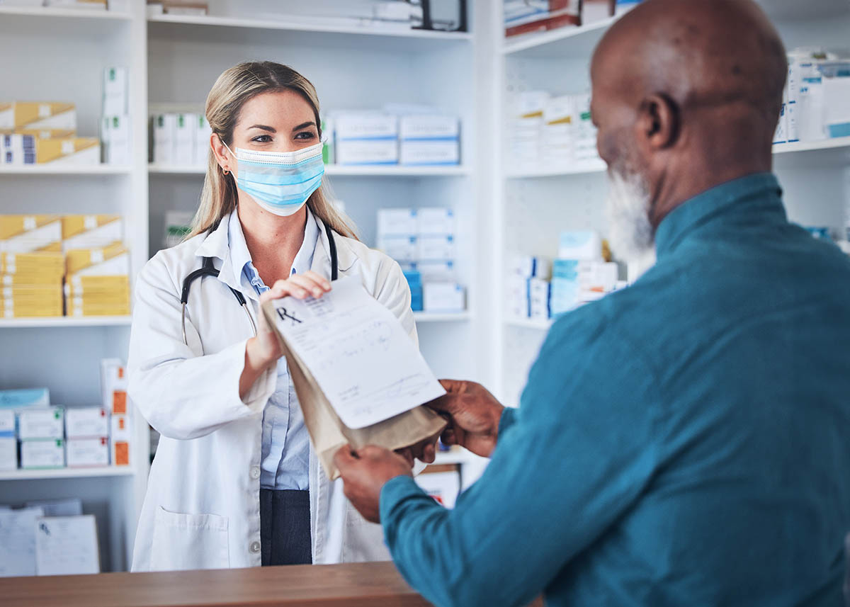 masked healthcare profesional handing prescription to patient