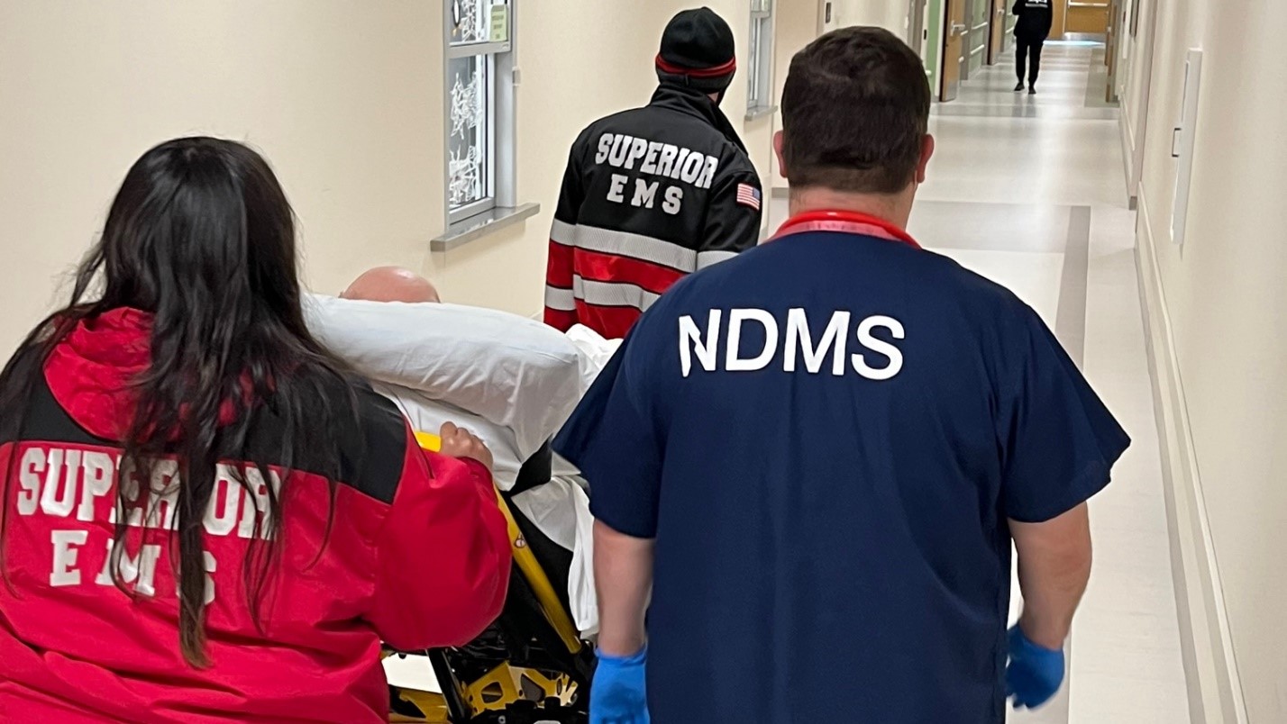 NDMS at regional hcc escorting a patient and EMS down a hallway