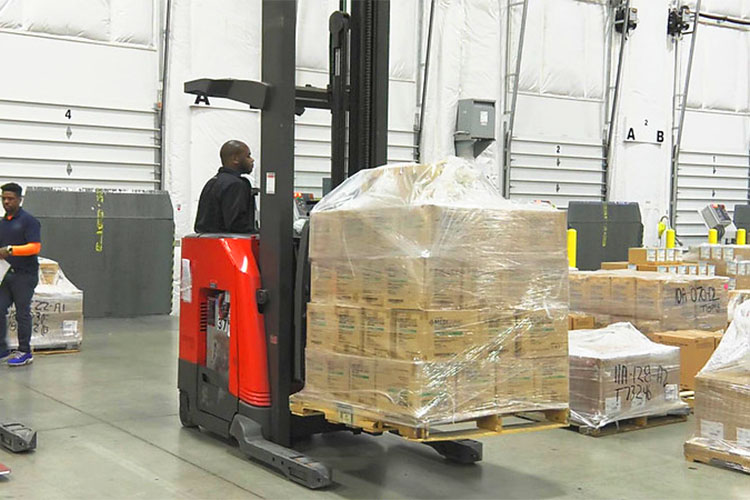 forklift in a warehouse moving a pallet of boxes
