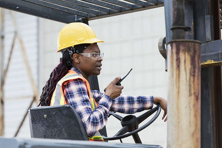 woman operting a forklift while on a walkie talkie