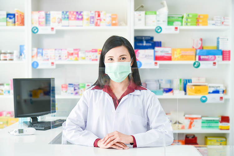 masked pharmacist standing behind pharmacy counter