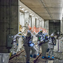 This figure is a photo of case study participants in a mock subway system, with equipment used to test for contamination.